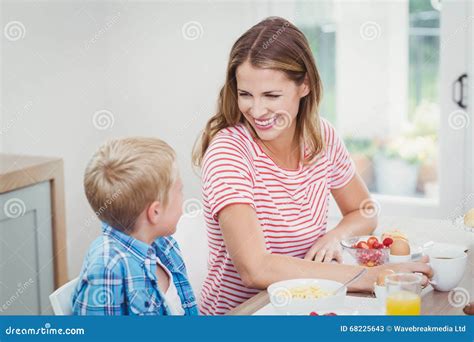 Madre E Hijo Que Sonríen Mientras Que Desayunando Imagen De Archivo