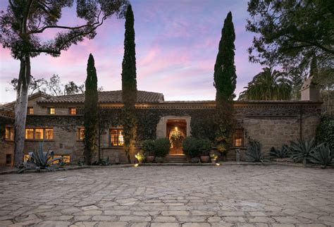 An Outdoor Courtyard With Stone Pavers And Potted Plants At Dusk In