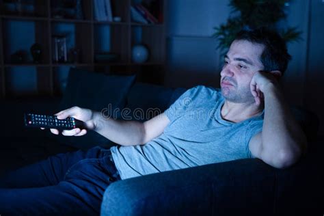 Bored Man Sitting On The Sofa Watching Television At Night Stock Image