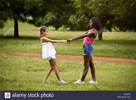 Two Hispanic And African Little Girls Playing Ring Around The Rosie In