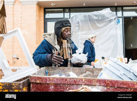 New York City, USA. Homeless African-American man searching a dumpster
