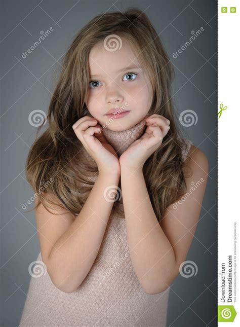 Retrato Da Menina Bonito Pequena Com Mãos Dobradas Perto Da Cara Foto