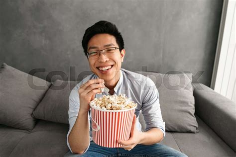 Portrait Of A Cheerful Young Asian Man Eating Popcorn Stock Image