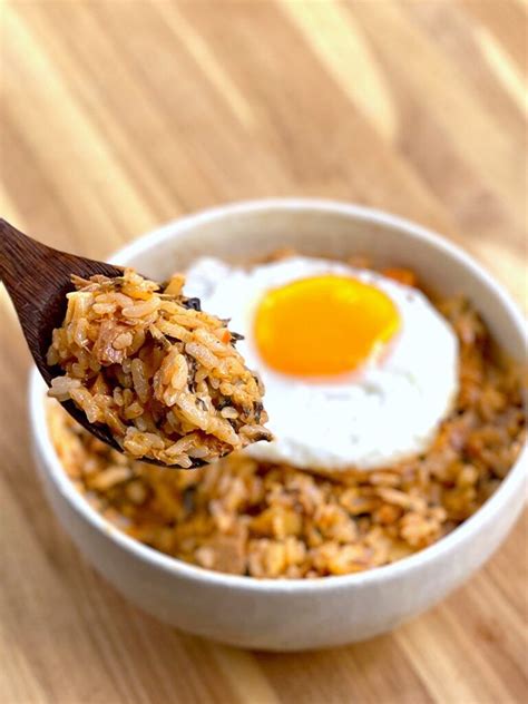 An Egg And Rice Dish Is Being Held By A Wooden Spoon With A Fried Egg