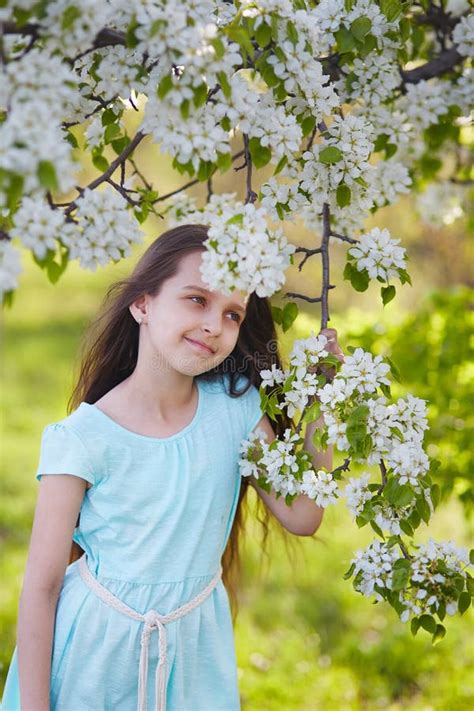 Beautiful Young Girl With A Dreamy Smile In A Blooming Apple Orchard