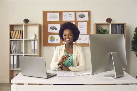 Happy Smiling Black Woman Sitting At Office Desk With Laptop And
