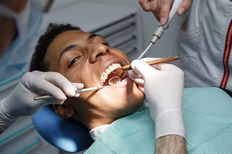 Cleanings Dentist Examining Oral Cavity Of Young African American Man