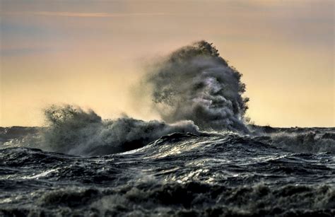 Dramatic slow motion of huge big waves smashing on concrete barrier wall that protects small marina at strong heavy winter storm in sea, early morning or evening low light. Can you sea it? Face appears in huge waves - Storytrender