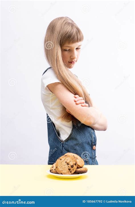 A Cute Girl Wants Cookies And Doubts About Her Choice Stock Photo