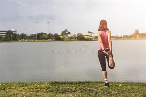 Young Fitness Woman Runner Stretching Legs Before Run On Park Stock