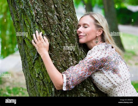 Blond Woman Hugging A Tree In A Park Stock Photo Alamy