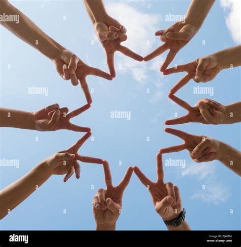 A Circle Of Ten Hands Making Peace Signs Under A Blue Sky With White