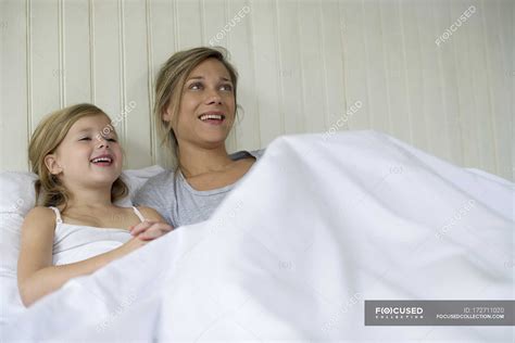 Madre e hija viendo televisión juntas en la cama Enfoque selectivo
