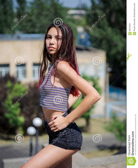 An Attractive Hipster Girl In Casual Clothes Sitting On An Urban