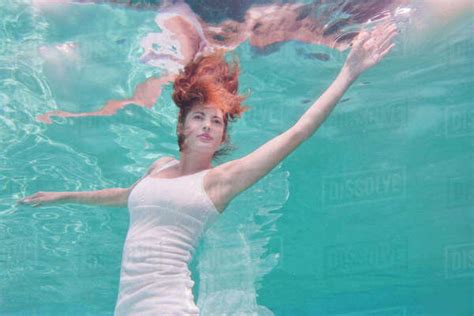 Underwater View Of Mixed Race Woman In Dress Swimming In Pool Stock