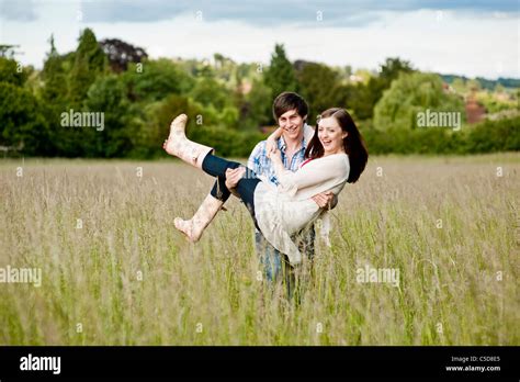 Young Man Carrying Woman In Love In A Field Stock Photo Alamy