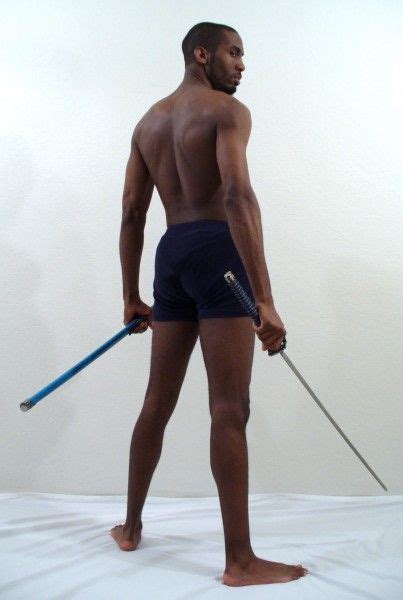 A Man With No Shirt Is Holding A Stick And Wearing Blue Trunks While