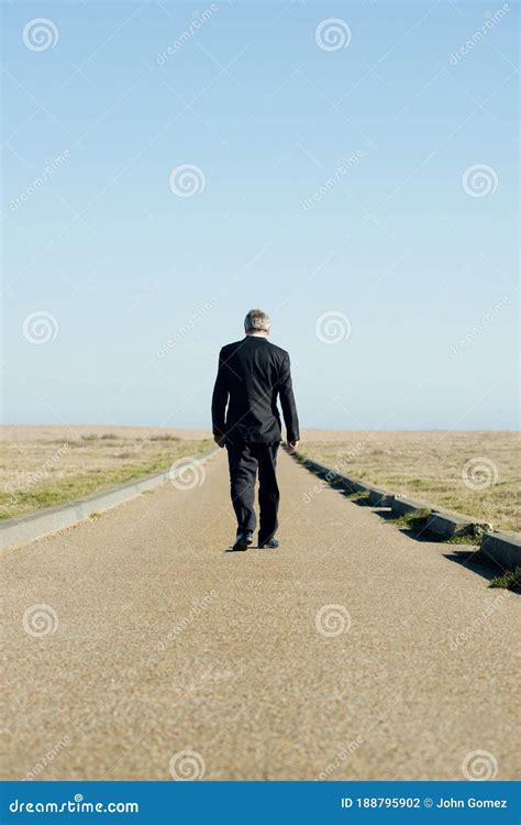 Businessman Walking Away Along A Never Ending Road Stock Photo Image