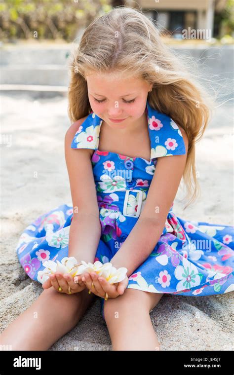 Outdoor Portrait Of Cute Petite Fille Blonde En Robe Fleurs Assis Sur La Plage De Sable