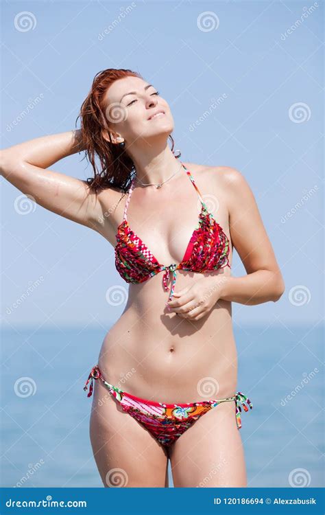 Mujer Joven Pelirroja En El Bikini Que Se Seca El Pelo En La Playa Foto