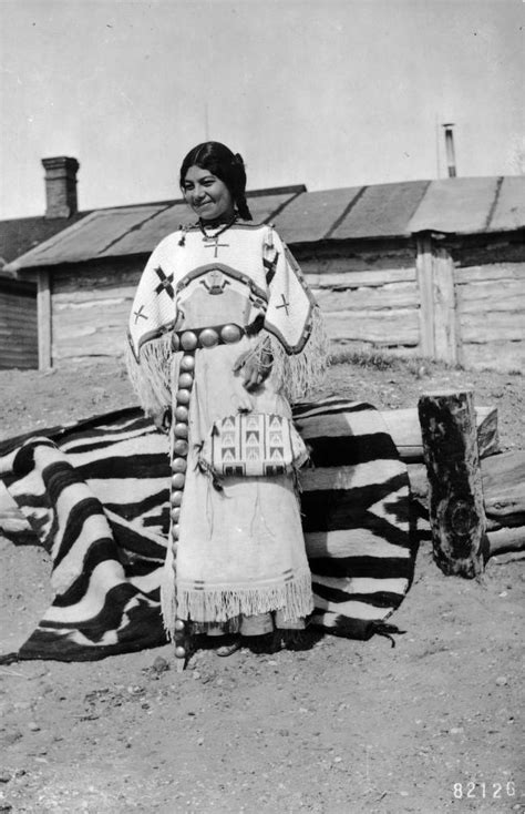 A Native American Dakota Sioux Woman Poses In Front Of A Hewn Log Building On A Blanket