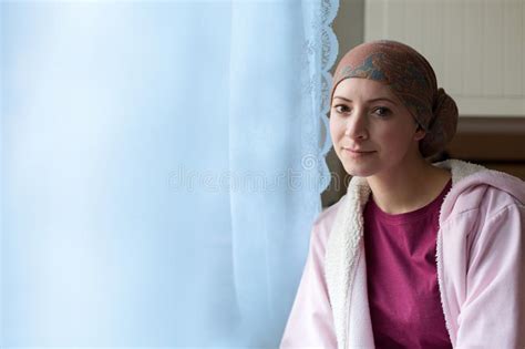 Young Positive Adult Female Cancer Patient Sitting In The Kitchen By A