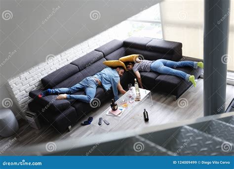 Drunk Friends Sleeping On Sofa In Messy Room After Party Stock Image