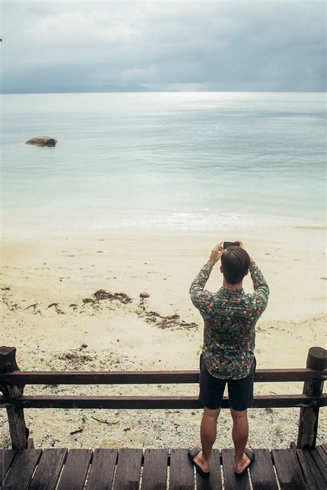 view of man from behind taking a picture of the beach del colaborador