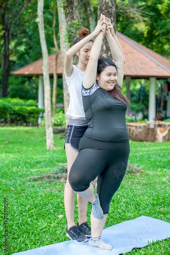asian thin and overweight woman doing the tree yoga pose together in park fat and fitness girls
