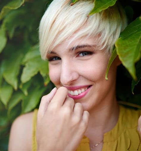 Beautiful Short Haired Platinum Blond Woman Standing Against An Ivy Fence Backdrop Stock Image