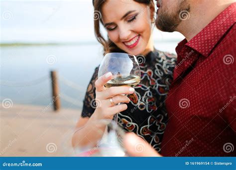 Esposo Besando A La Esposa Y Manteniendo El Vaso De Vino Blanco Con El Lago En El Suelo Foto De
