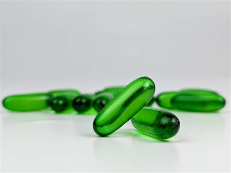 green transparent capsule pills of vitamin E isolated on white