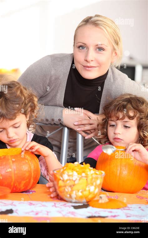 Woman Helping Her Children Carve Pumpkins Stock Photo Alamy