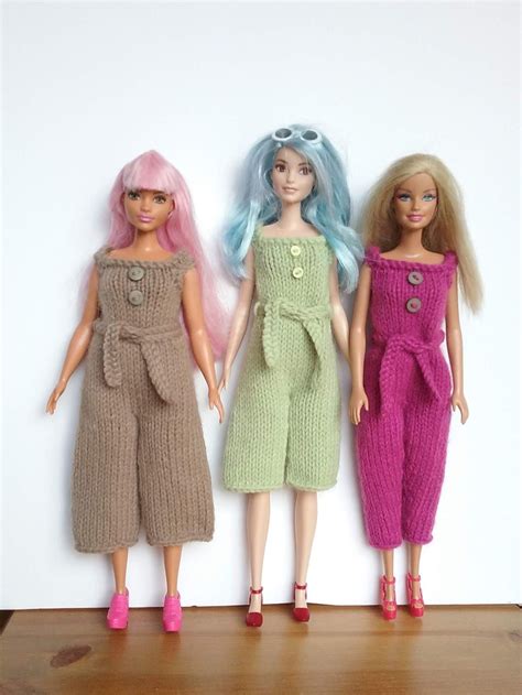three dolls standing next to each other in front of a white wall with pink and blue hair