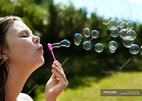Girl Blowing Bubbles Outdoors Focus On Foreground Sunlight Nature Stock Photo