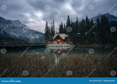Wooden Cottage Glowing With Pine Forest And Bridge Reflection On