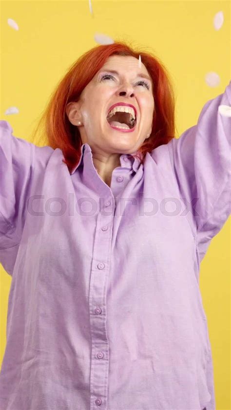 redheaded mature woman surrounded by confetti flying in the air stock video colourbox