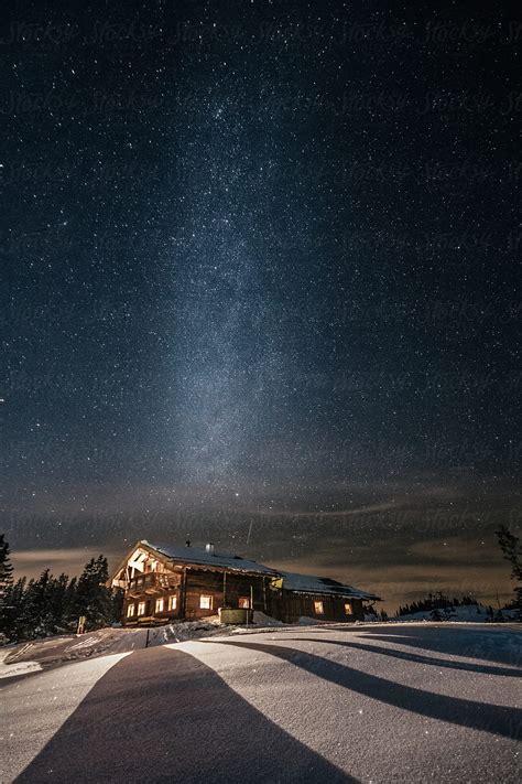 Alpine Cabin In Snowy Mountain Landscape At Night With The Milky Way