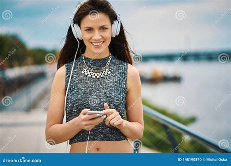 Beautiful Woman With White Headphones Listens Music While Walking By