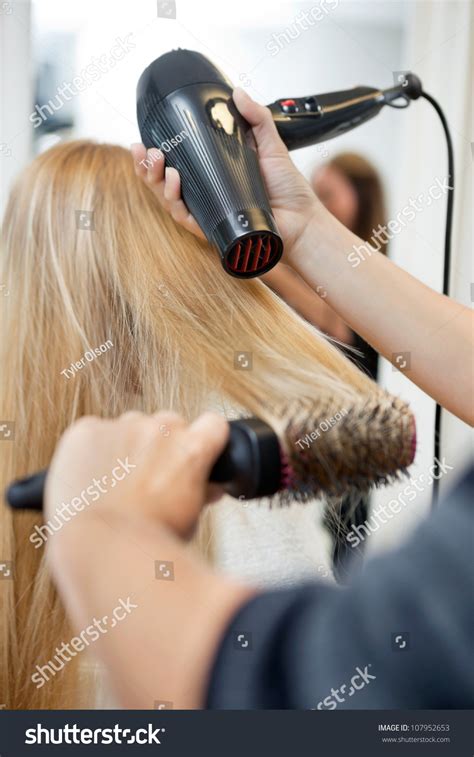 This brush is ideal for finer hair because it helps create volume and body with the help of the boar bristles. Close Up Of Hairdressers Hands Drying Long Blond Hair With ...