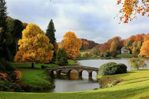 A Bridge Over A Body Of Water Surrounded By Trees With Yellow Leaves On