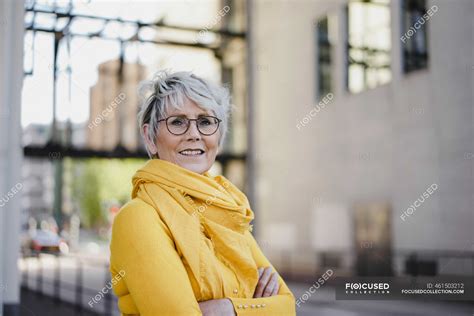 Portrait Of Mature Woman With Grey Hair Wearing Glasses And Yellow