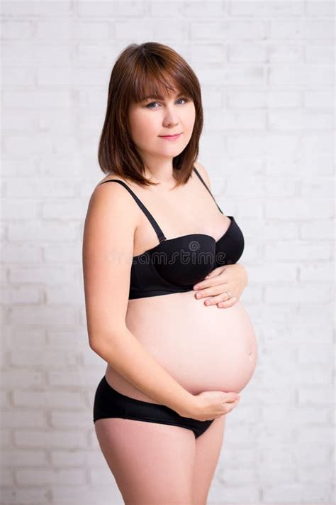 retrato da mulher gravida na roupa interior que toca em sua barriga sobre w foto de stock