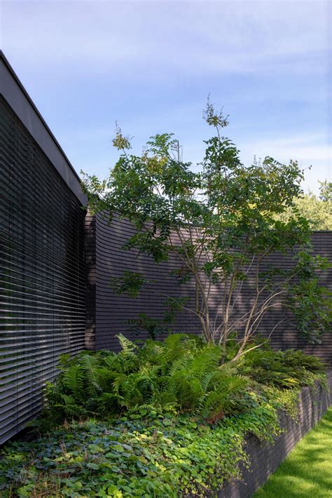 This Home Combines A Black Brick Exterior With Large Glass Walls For A