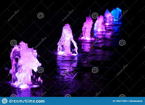Fragment Of The Purple Water Fountains On The Black Background Stock