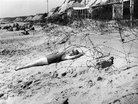A Woman Sunbathes On A Wartime Bank Holiday Surrounded By Barbed Wire