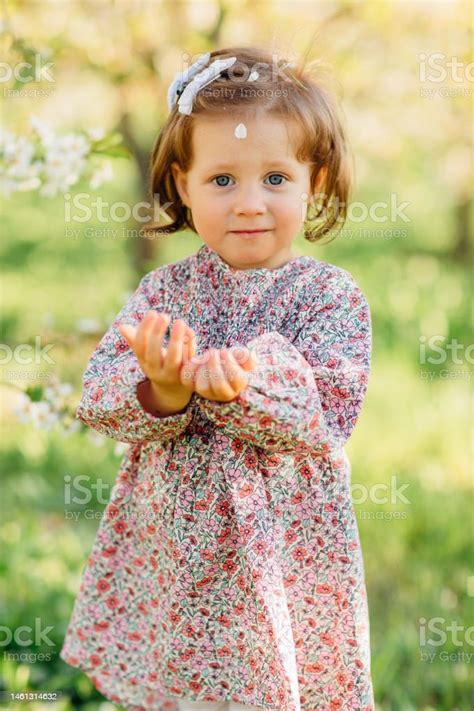 A Pretty Kid Girl By A Flowering Tree In A Spring Garden Stock Photo