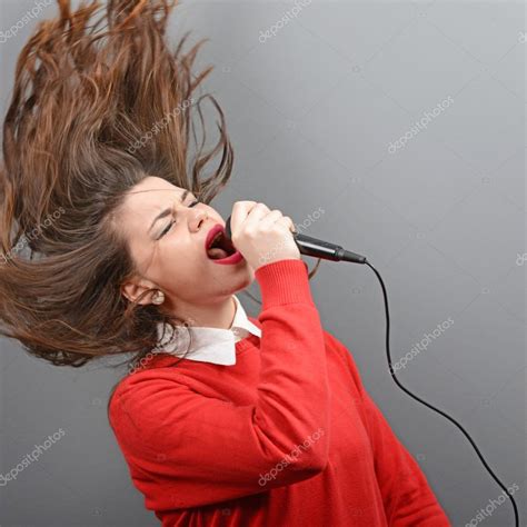 Beautiful Woman Singing With The Microphone Against Gray Backgro
