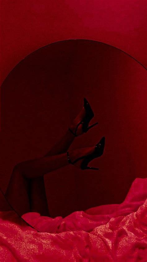 A Womans Legs In High Heeled Shoes On A Bed With Red Sheets