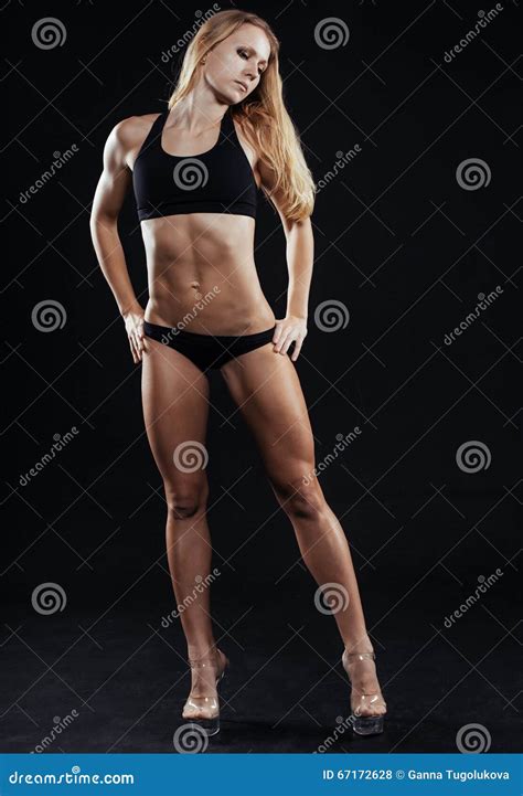 Metta In Mostra La Donna Di Forma Fisica Con I Forti Muscoli Su Fondo Nero Fotografia Stock
